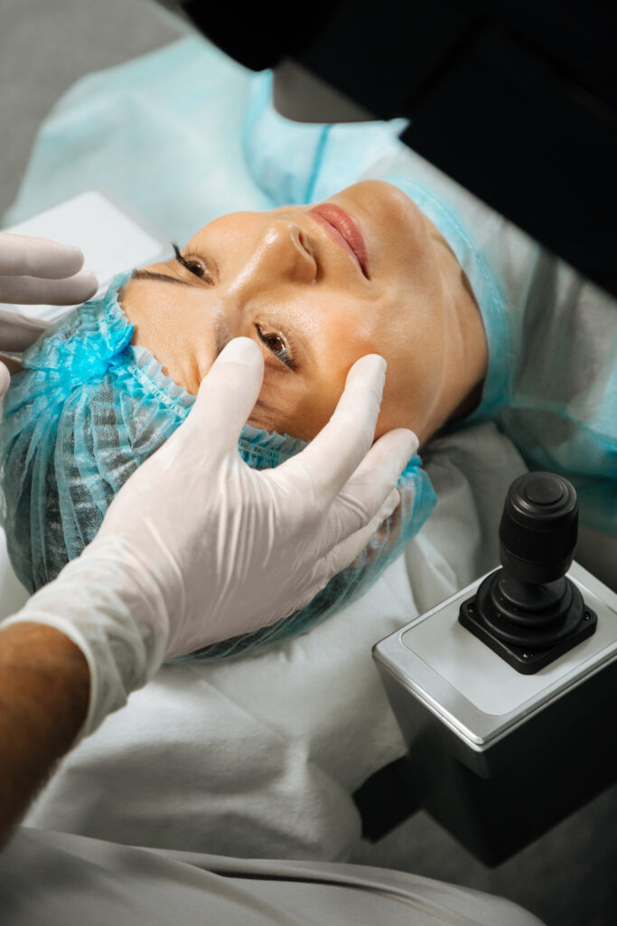 Il dottore tende la pelle sulla fronte di una paziente distesa sul tavolo chirurgico prima dell'intervento di lifting.